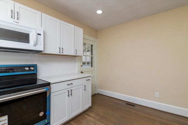 kitchen featuring white cabinets, white microwave, and stainless steel electric stove