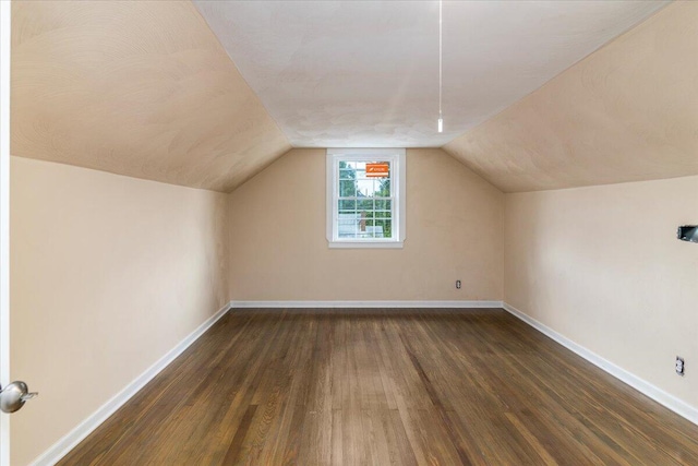 additional living space featuring lofted ceiling, dark wood-style flooring, and baseboards