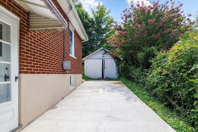 view of side of home with a patio area, a shed, an outbuilding, and brick siding