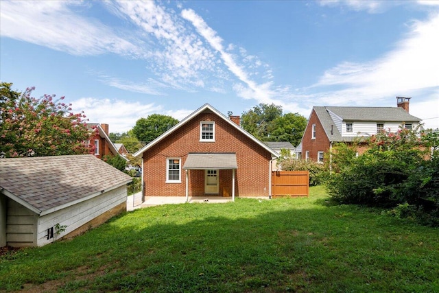 back of house featuring a yard, brick siding, a chimney, and fence