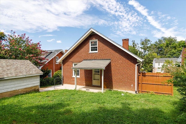 back of property featuring brick siding, a lawn, a chimney, and fence