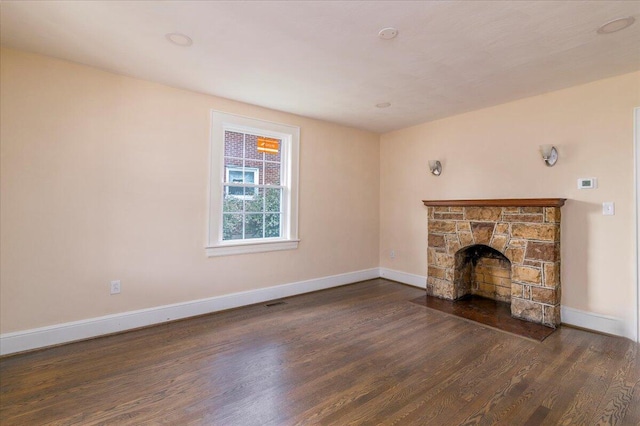 unfurnished living room with a fireplace, baseboards, and dark wood-style flooring