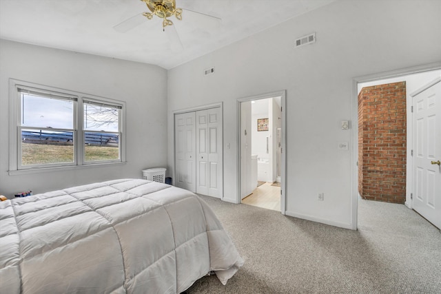 bedroom with visible vents, lofted ceiling, a closet, light colored carpet, and connected bathroom