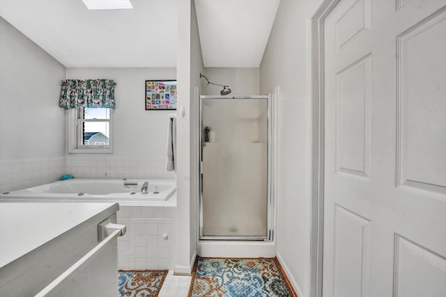 full bathroom featuring tile patterned flooring, a shower stall, a skylight, and a garden tub