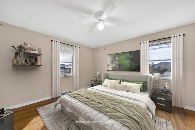 bedroom with baseboards, multiple windows, and wood finished floors