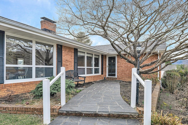 entrance to property with brick siding and a chimney