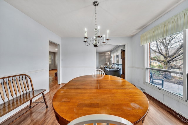 dining room with an inviting chandelier, wood finished floors, a wainscoted wall, and visible vents