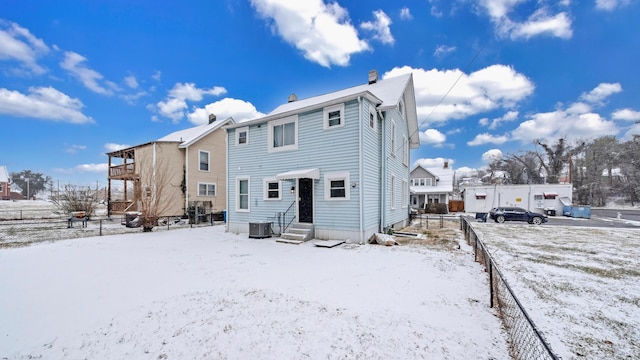 snow covered house with central air condition unit and entry steps