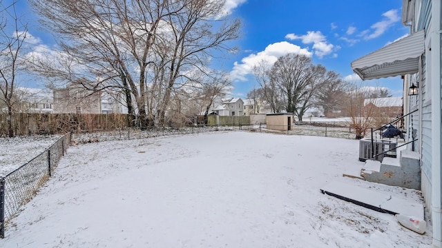 yard covered in snow featuring fence and central AC unit