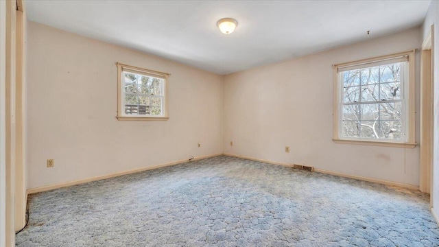 spare room with carpet, visible vents, and baseboards