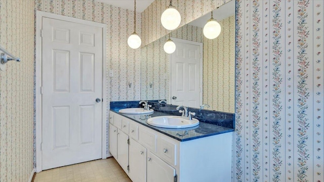 full bathroom with double vanity, wallpapered walls, and a sink