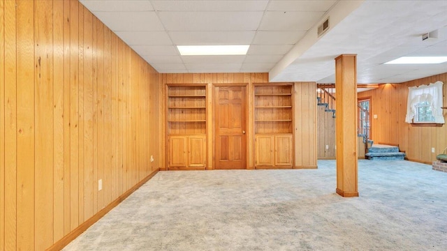 below grade area with carpet, wooden walls, stairway, and built in features