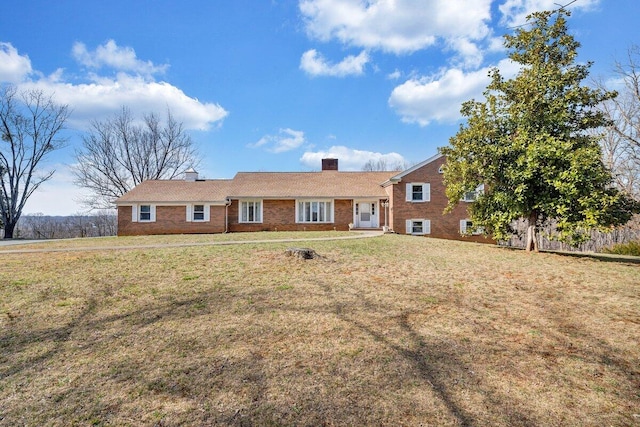 view of front facade with a front yard, brick siding, and a chimney