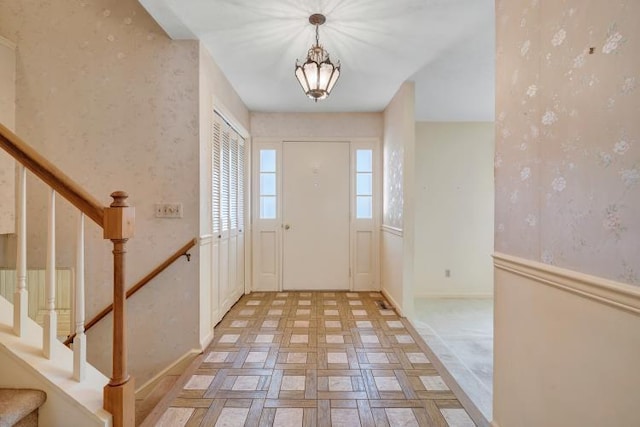 entrance foyer with baseboards, stairs, and wallpapered walls