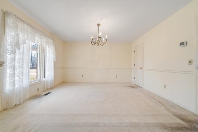 spare room featuring an inviting chandelier, carpet, and visible vents