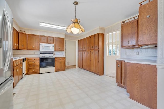 kitchen with decorative light fixtures, white appliances, brown cabinetry, light countertops, and light floors