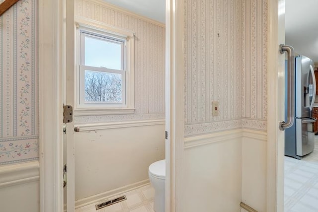 bathroom featuring visible vents, wallpapered walls, wainscoting, tile patterned floors, and toilet