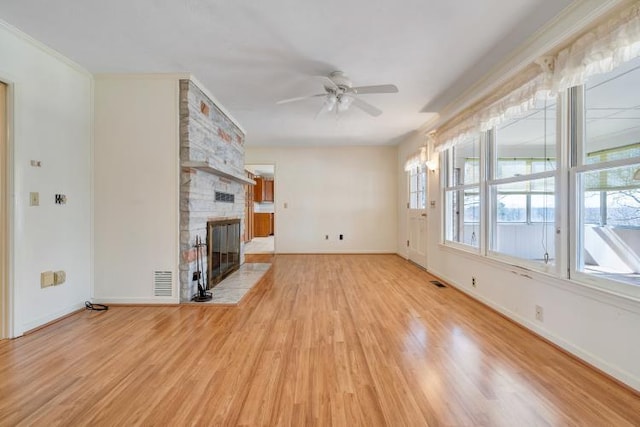 unfurnished living room with a ceiling fan, visible vents, baseboards, a fireplace, and light wood-type flooring