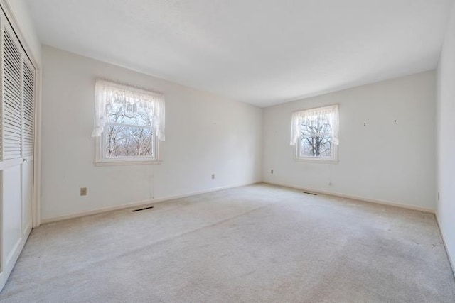 unfurnished bedroom with a closet, light carpet, and baseboards