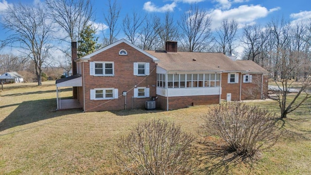 rear view of house featuring brick siding, central AC, a chimney, a yard, and a sunroom