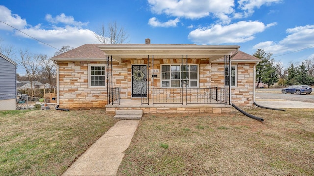 bungalow-style house with a porch, fence, stone siding, a chimney, and a front yard