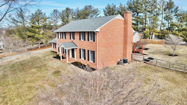 view of property exterior featuring a yard, a chimney, fence, and brick siding