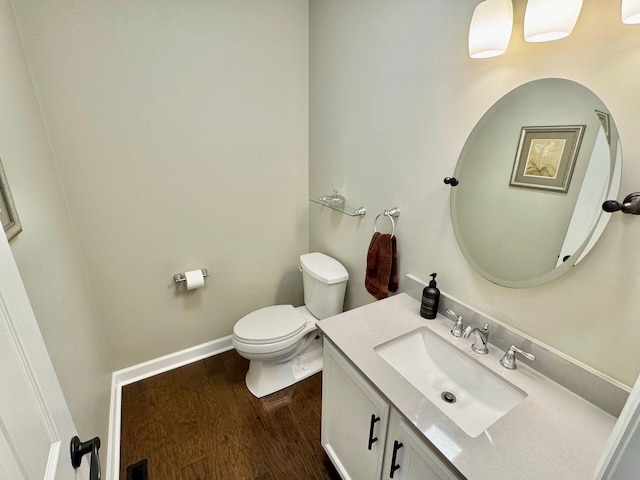 half bath featuring visible vents, toilet, vanity, wood finished floors, and baseboards