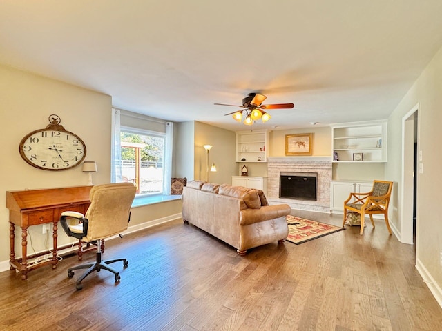 living area with a fireplace with raised hearth, wood finished floors, and baseboards