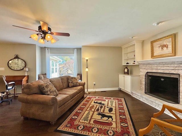 living area with dark wood-style floors, ceiling fan, a fireplace, and baseboards