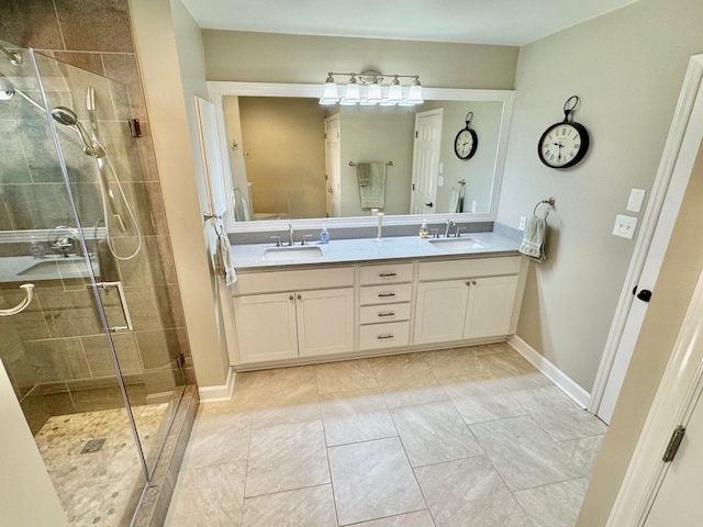 full bath with double vanity, a stall shower, baseboards, and a sink