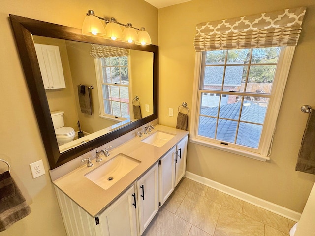 bathroom with double vanity, a sink, and a healthy amount of sunlight