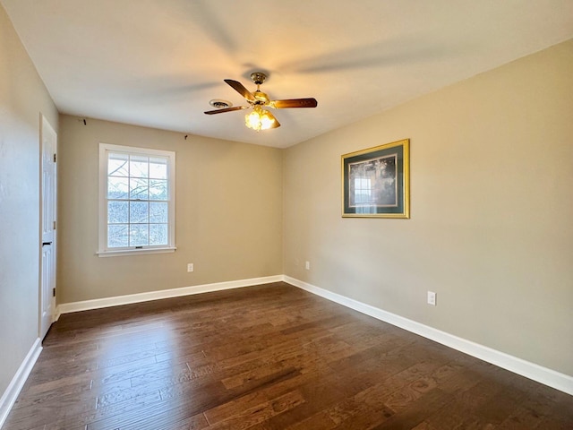 empty room with a ceiling fan, dark wood finished floors, and baseboards