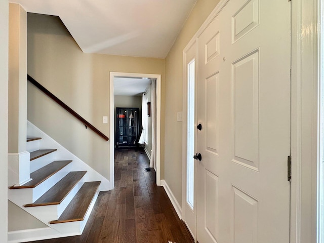 foyer with dark wood-style floors, baseboards, and stairs