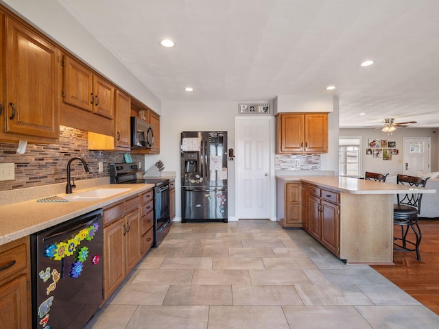 kitchen featuring black appliances, a breakfast bar, a peninsula, and light countertops