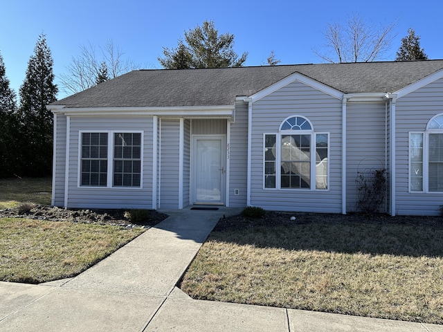 view of front facade featuring roof with shingles and a front yard