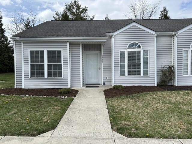 view of front of home with a shingled roof and a front lawn