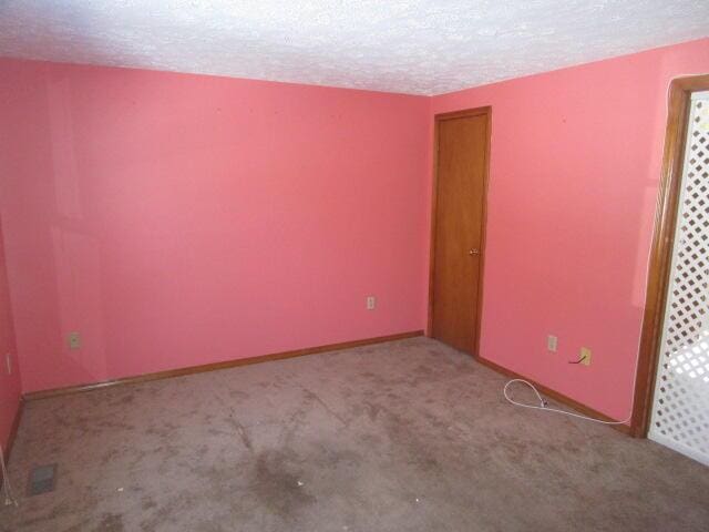 carpeted empty room with a textured ceiling