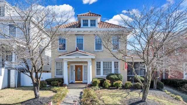 view of front of home with a sunroom, brick siding, fence, and a front lawn