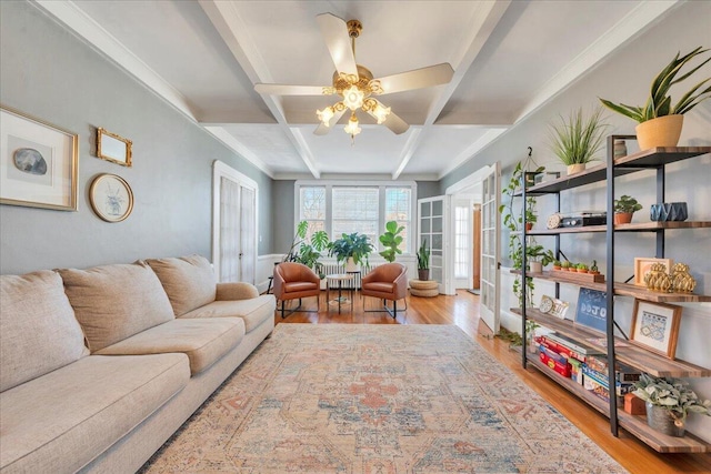 living room with ceiling fan, coffered ceiling, wood finished floors, and beamed ceiling