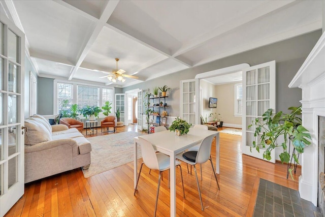 dining space featuring french doors, coffered ceiling, a fireplace, and hardwood / wood-style flooring