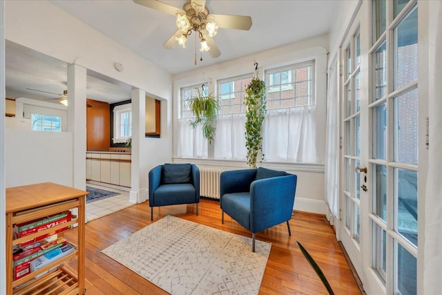 living area with a ceiling fan, radiator, baseboards, and hardwood / wood-style flooring