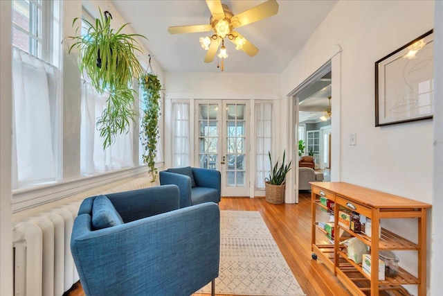 sitting room featuring ceiling fan, french doors, wood finished floors, and a healthy amount of sunlight