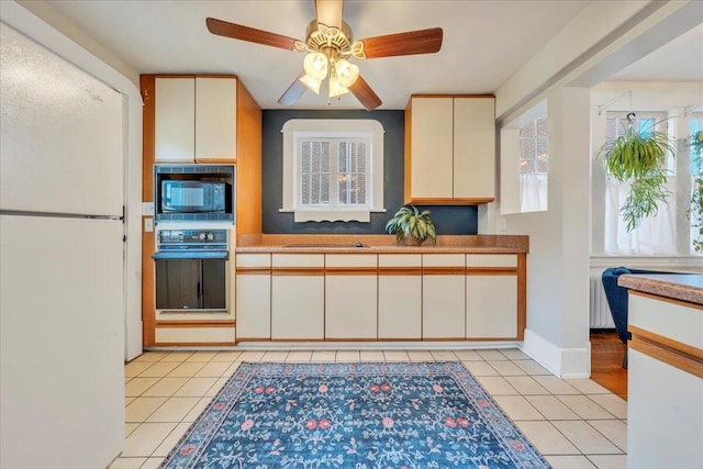 kitchen with black appliances, radiator heating unit, light tile patterned flooring, and baseboards