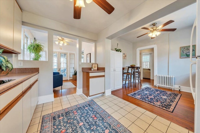 kitchen with light tile patterned floors, radiator heating unit, a wealth of natural light, and french doors