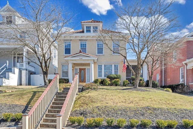 view of front facade with fence, stairway, a front lawn, and brick siding