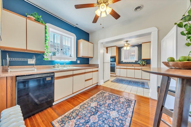 kitchen with black appliances, visible vents, light wood finished floors, and a sink