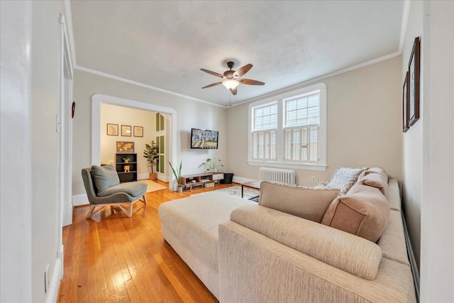 living room with ornamental molding, light wood-type flooring, radiator, and a ceiling fan