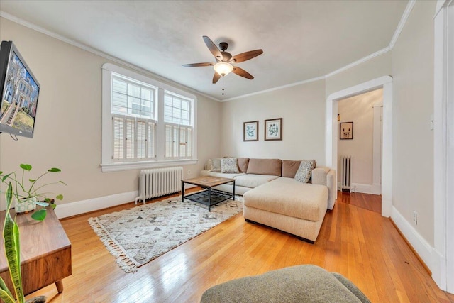 living area featuring baseboards, crown molding, radiator heating unit, and wood finished floors