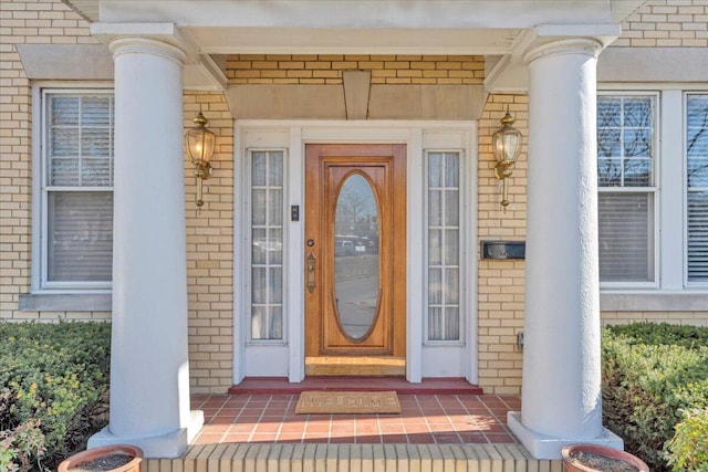 property entrance with covered porch and brick siding