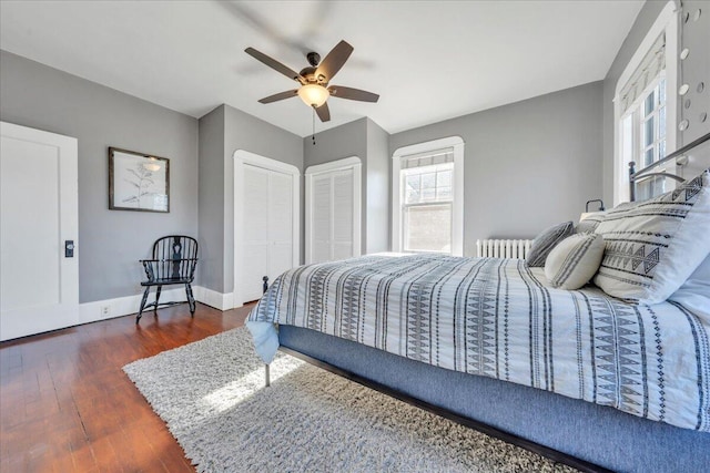 bedroom featuring a ceiling fan, wood finished floors, two closets, and baseboards